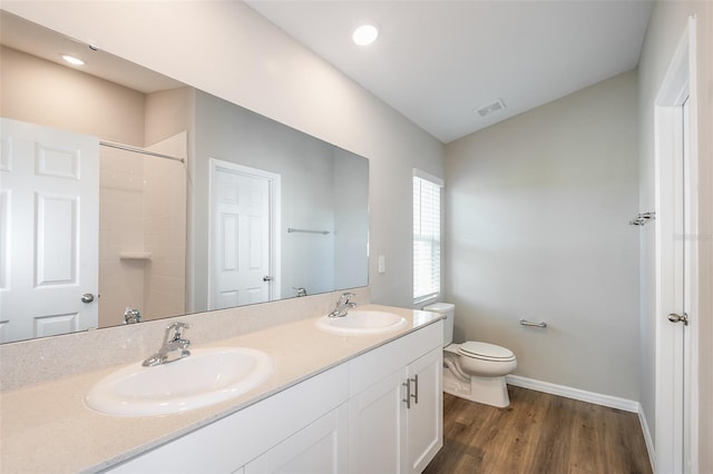 bathroom with toilet, visible vents, a sink, and wood finished floors