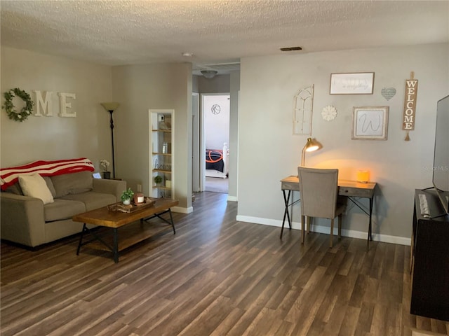 living room featuring dark wood-type flooring and a textured ceiling