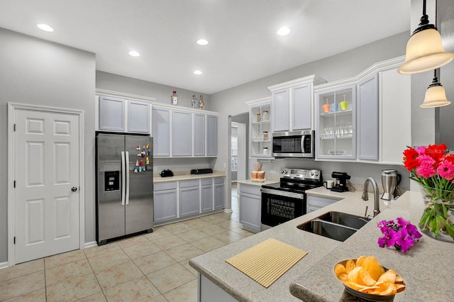 kitchen featuring pendant lighting, white cabinets, sink, appliances with stainless steel finishes, and light tile patterned flooring