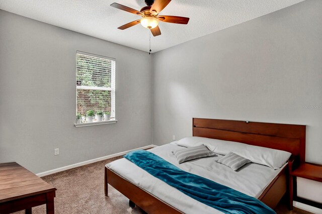 carpeted bedroom featuring ceiling fan and a textured ceiling