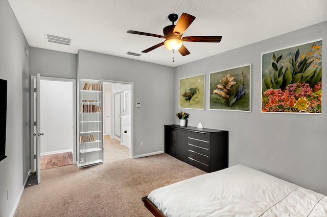 bedroom featuring ceiling fan, light colored carpet, and a textured ceiling