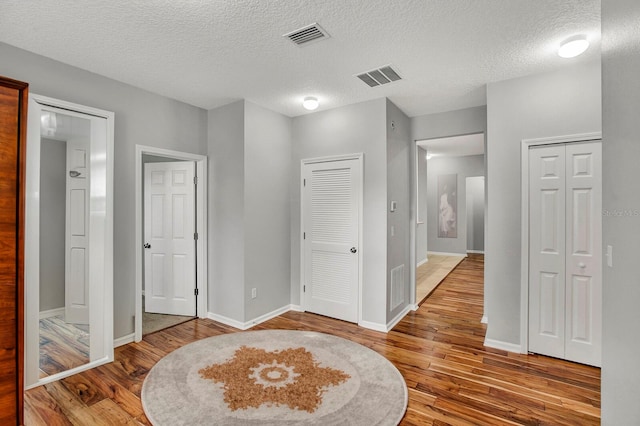 bedroom featuring wood-type flooring, a textured ceiling, and two closets