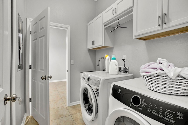 laundry room with washer and clothes dryer, light tile patterned floors, and cabinets