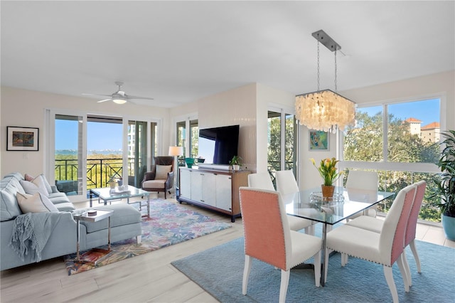 dining area with plenty of natural light, ceiling fan with notable chandelier, and light hardwood / wood-style flooring