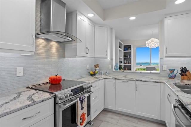 kitchen with light stone counters, white cabinetry, stainless steel appliances, and wall chimney range hood