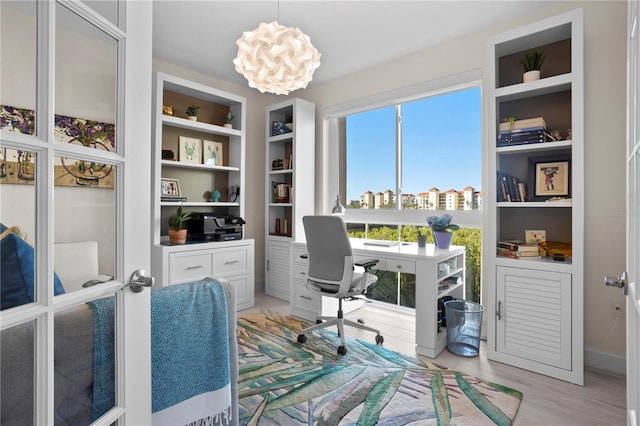 office area with light hardwood / wood-style flooring, a chandelier, and built in features