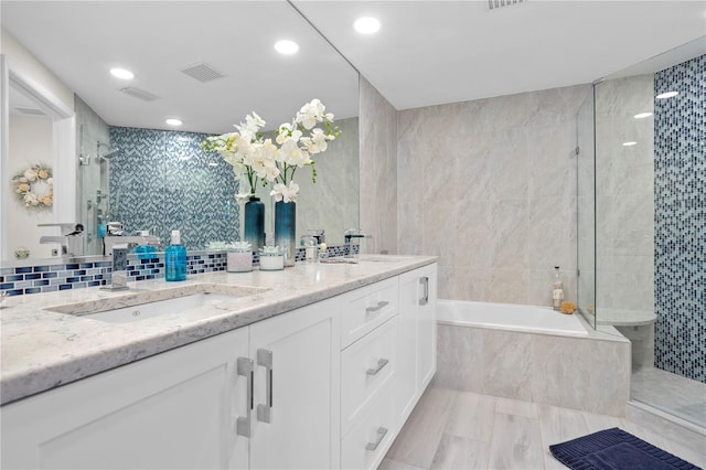 bathroom featuring shower with separate bathtub, vanity, and tile walls