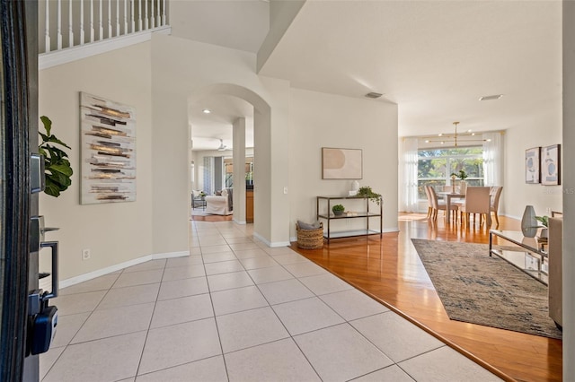 foyer with ceiling fan with notable chandelier and light hardwood / wood-style flooring