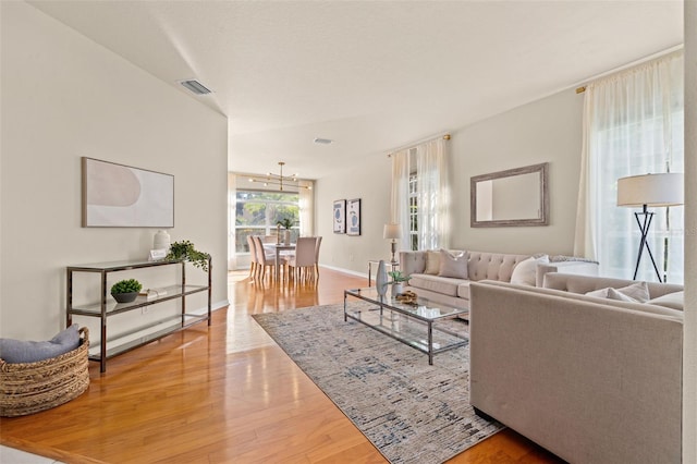 living room with hardwood / wood-style flooring and a notable chandelier