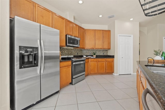 kitchen with tasteful backsplash, light tile patterned floors, dark stone counters, and appliances with stainless steel finishes