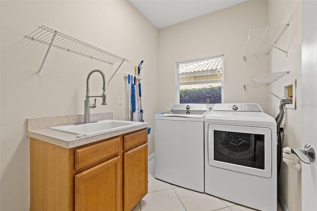 clothes washing area with sink, light tile patterned floors, cabinets, and independent washer and dryer