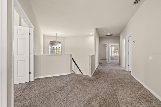 hall featuring a notable chandelier, carpet floors, and a wealth of natural light