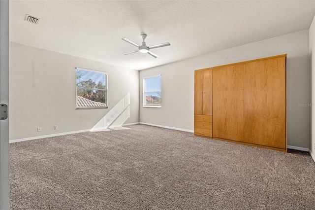 unfurnished bedroom featuring ceiling fan, a closet, carpet floors, and a textured ceiling