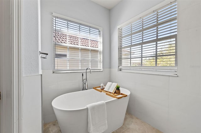 bathroom featuring tile patterned floors, a bathtub, and tile walls