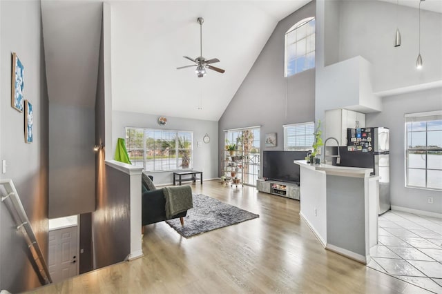 living room featuring ceiling fan, high vaulted ceiling, and light hardwood / wood-style flooring