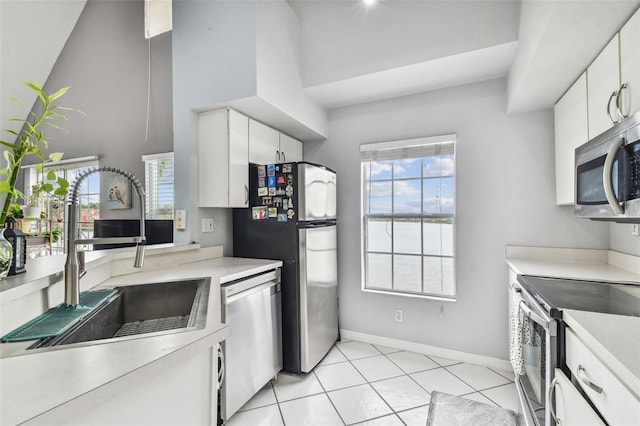 kitchen with white cabinets, light tile patterned floors, stainless steel appliances, and sink