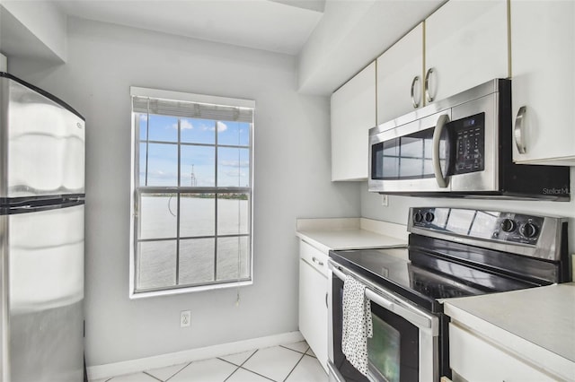 kitchen featuring white cabinetry, a water view, stainless steel appliances, and light tile patterned floors