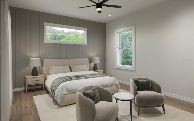 bedroom with ceiling fan, light hardwood / wood-style floors, and wooden walls