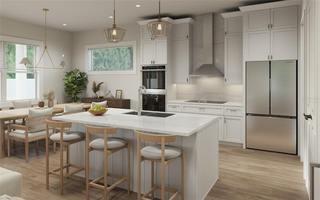 kitchen featuring decorative backsplash, hanging light fixtures, black appliances, and wall chimney exhaust hood