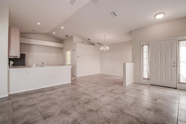 entrance foyer featuring an inviting chandelier, lofted ceiling, and sink