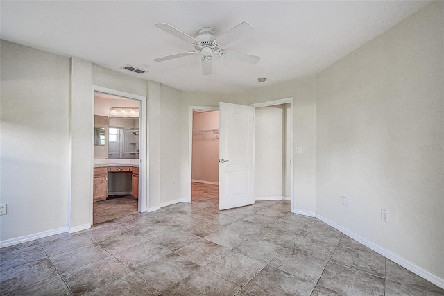 unfurnished bedroom with connected bathroom, a closet, a spacious closet, and ceiling fan