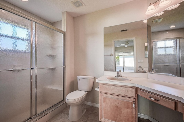 bathroom with vanity, a shower with door, tile patterned floors, ceiling fan, and toilet