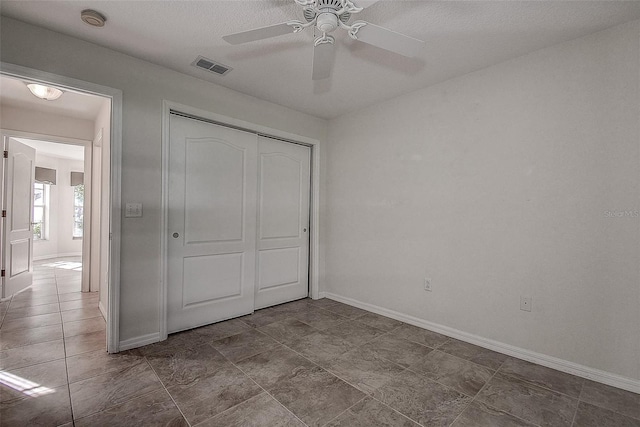 unfurnished bedroom with a textured ceiling, a closet, and ceiling fan