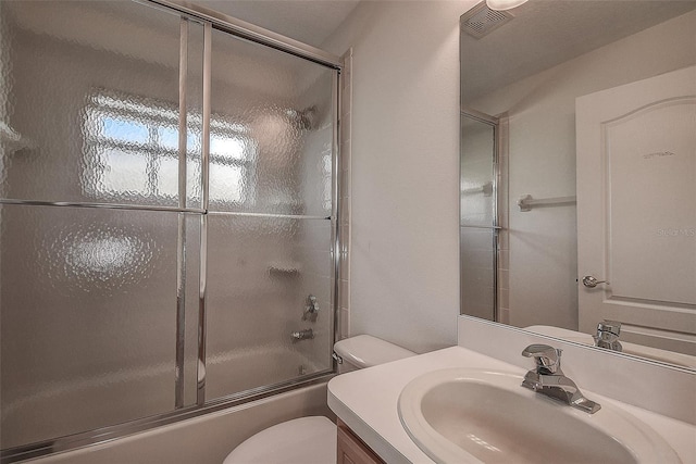 full bathroom featuring vanity, toilet, and shower / bath combination with glass door