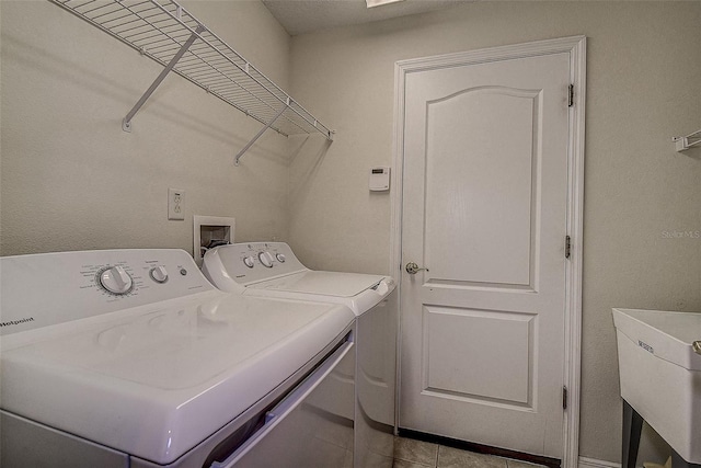 laundry area featuring washer and clothes dryer, light tile patterned floors, and sink