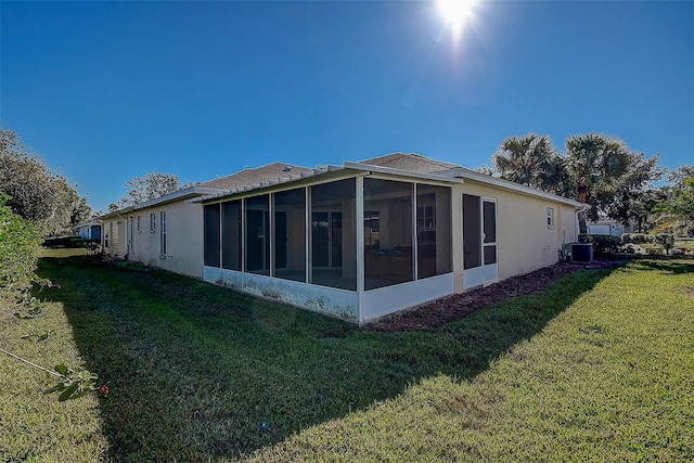 view of property exterior featuring a yard, a sunroom, and central air condition unit