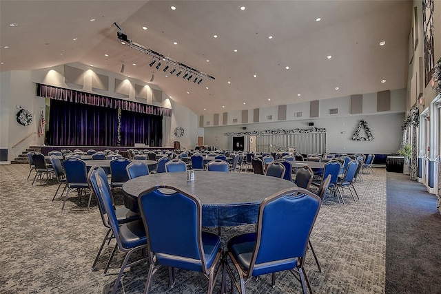 carpeted dining space with high vaulted ceiling