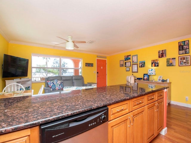 kitchen with crown molding, stainless steel dishwasher, dark stone countertops, and light wood-type flooring