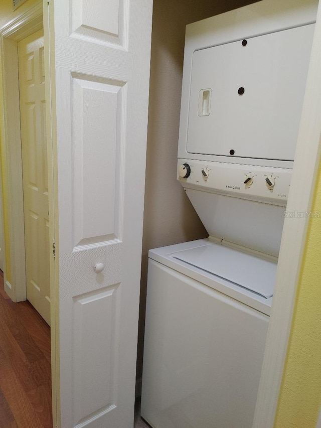 clothes washing area featuring hardwood / wood-style flooring and stacked washer / dryer