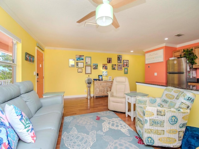 living room featuring crown molding, ceiling fan, and light wood-type flooring