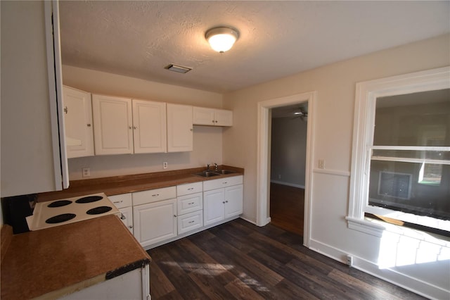 kitchen featuring dark wood-type flooring, white cabinets, sink, electric range, and a textured ceiling