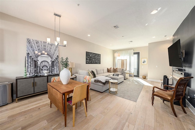 living room with light hardwood / wood-style floors and a notable chandelier