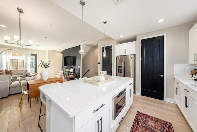 kitchen featuring white cabinets, a kitchen island, light wood-type flooring, and pendant lighting