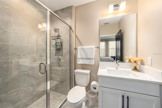 bathroom featuring vanity, toilet, and a shower with shower door