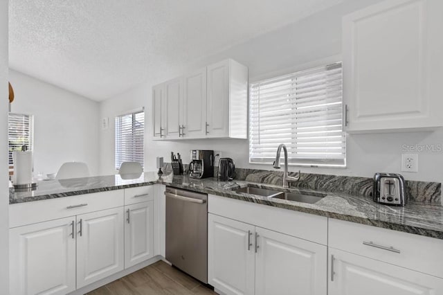 kitchen with dishwasher, white cabinets, dark stone counters, and sink