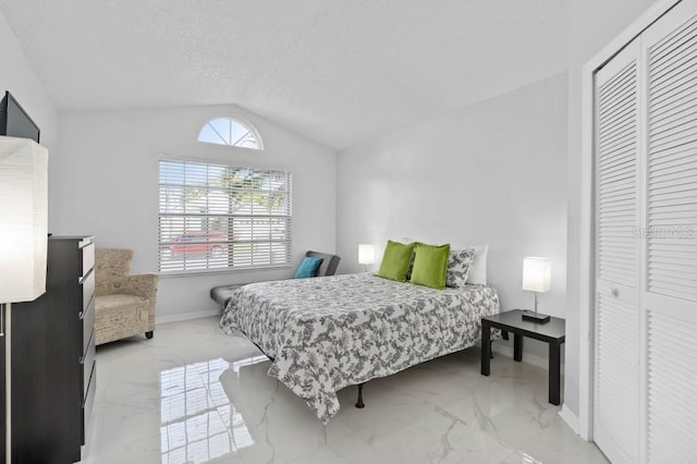 bedroom with a closet, a textured ceiling, and vaulted ceiling