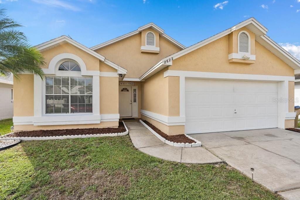 2622 Montego Bay Blvd, Kissimmee, FL 34746 - view of front facade featuring stucco siding, a garage, and concrete driveway