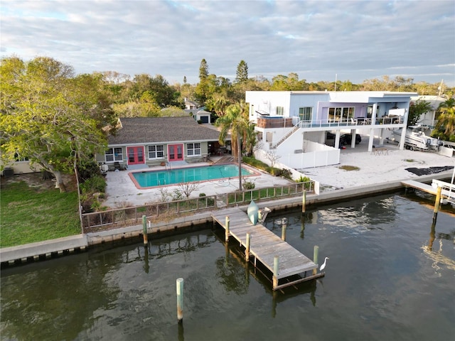 back of house with an outdoor pool, a patio area, a water view, and fence