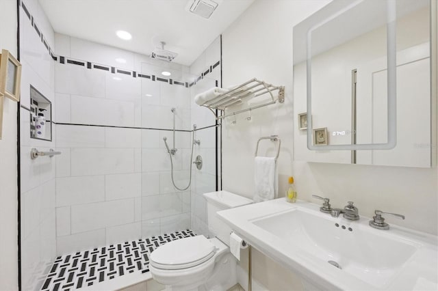 bathroom featuring toilet, sink, and a tile shower