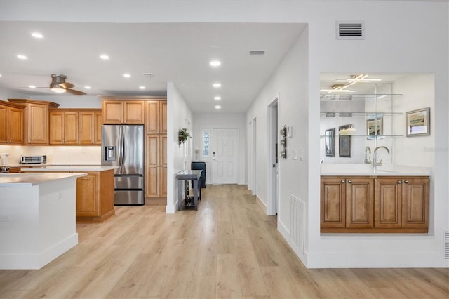 kitchen featuring ceiling fan, stainless steel fridge, sink, and light hardwood / wood-style flooring