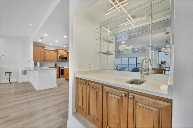 bar with hanging light fixtures, light hardwood / wood-style floors, sink, and appliances with stainless steel finishes