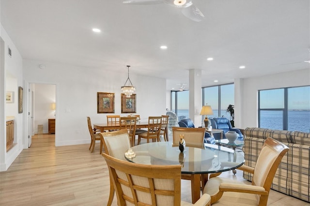 dining space featuring ceiling fan, a water view, and light wood-type flooring