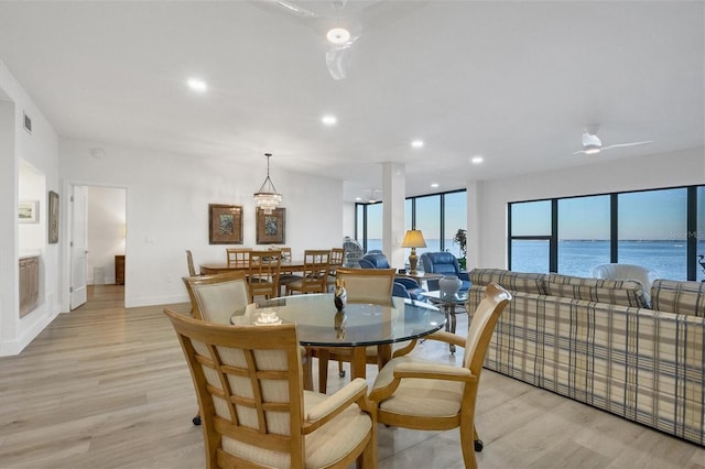 dining room with a water view and light hardwood / wood-style floors