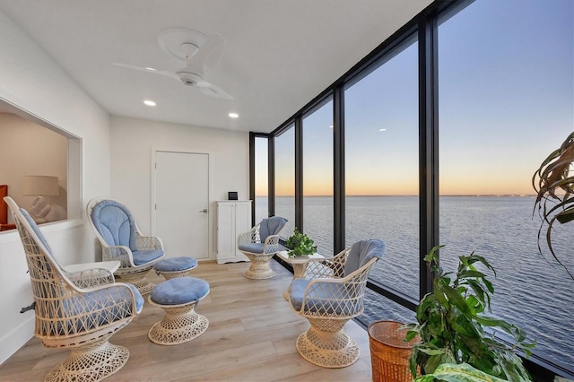 sunroom / solarium with ceiling fan and a water view