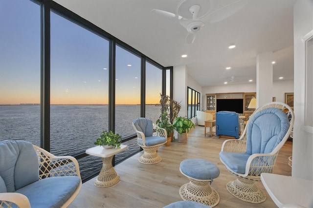 interior space featuring a water view, expansive windows, hardwood / wood-style flooring, and ceiling fan