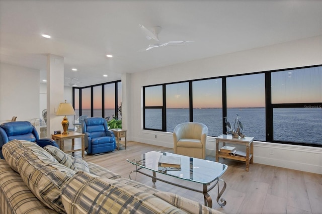 living room with ceiling fan, light hardwood / wood-style floors, and a water view